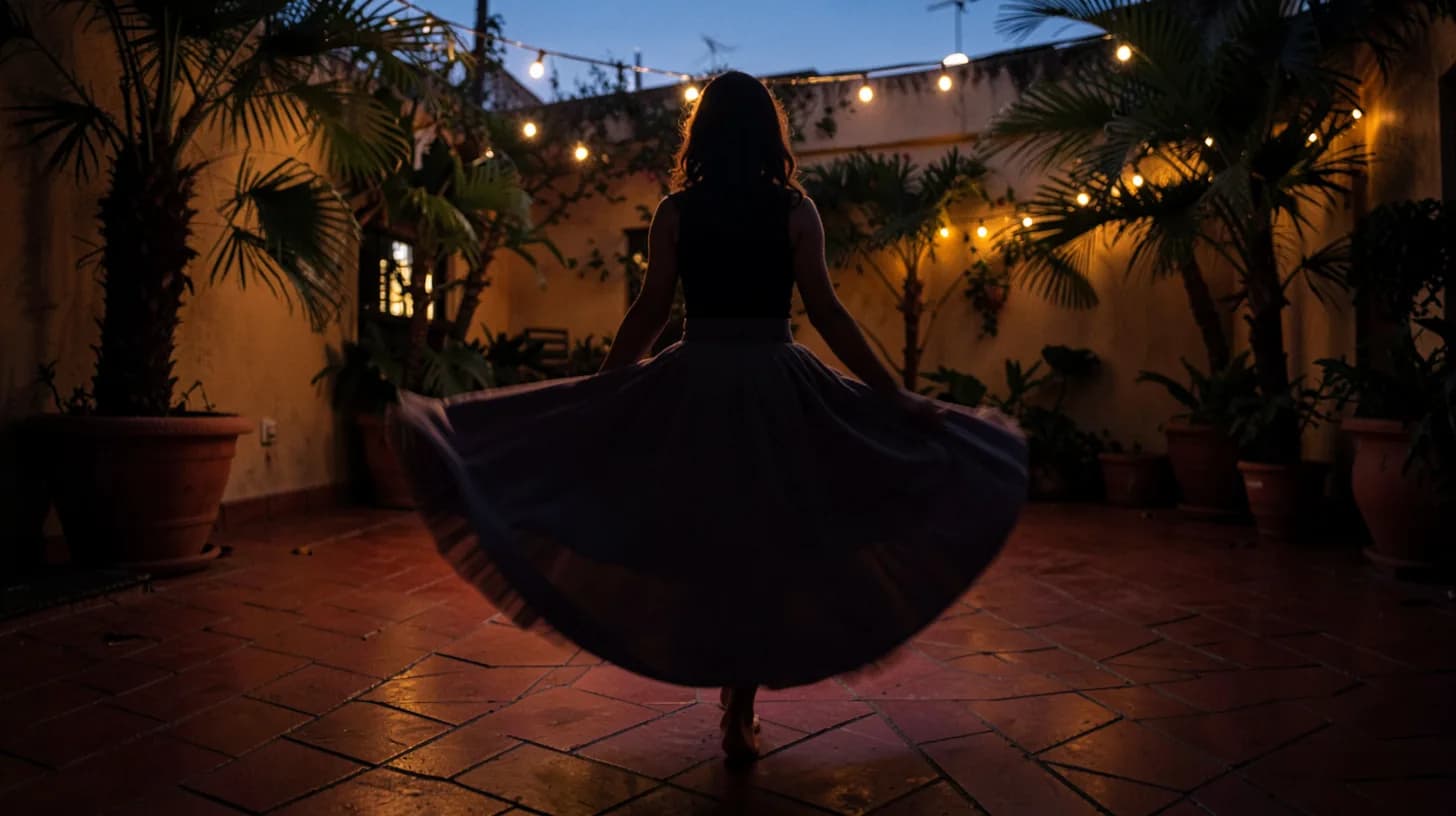 Silhouette of a woman mid-turn in a wide skirt on a tiled patio at dusk, the fabric blurred by movement.